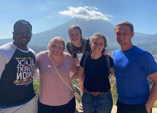 五名学生微笑着拍摄以火山为背景的照片